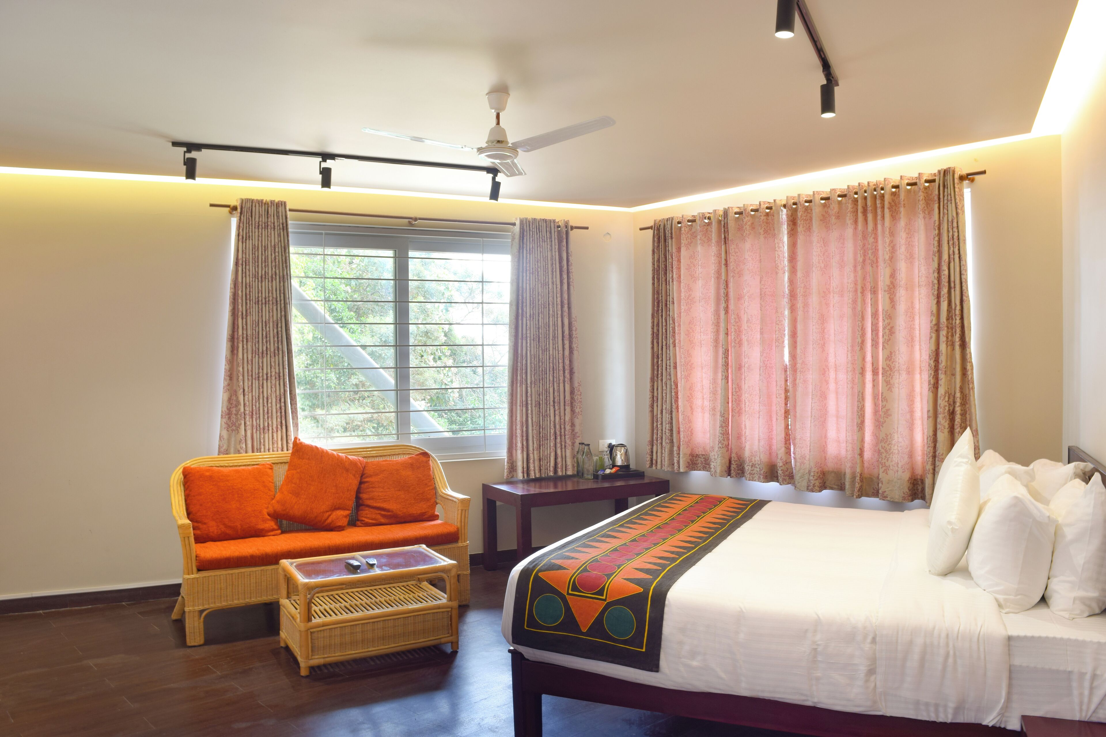 Una habitación de hotel con cama, sofá, mesa y ventana con cortinas.