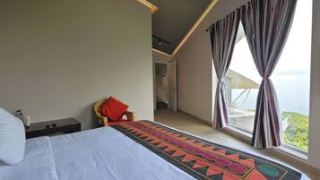 Un dormitorio con una cama grande, una mesita de noche, una silla y vistas al exterior.