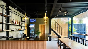 A restaurant with a long wooden counter, shelves with bottles, and a TV screen. - Mayfair Garden Resort (Panglao)