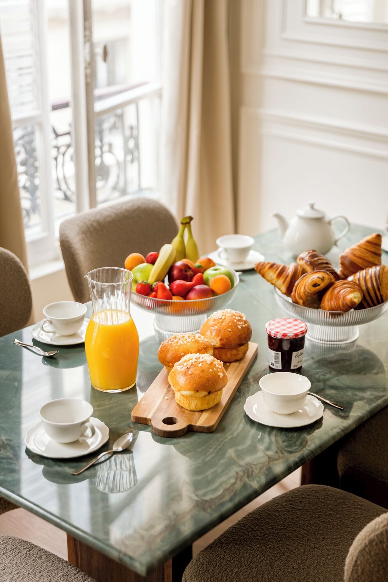 A breakfast table with a variety of pastries, fruits, and a glass of orange juice.