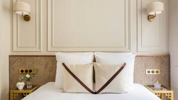 A neatly made bed with two pillows, a bedside table with a vase and a decorative item, and wall-mounted lamps.