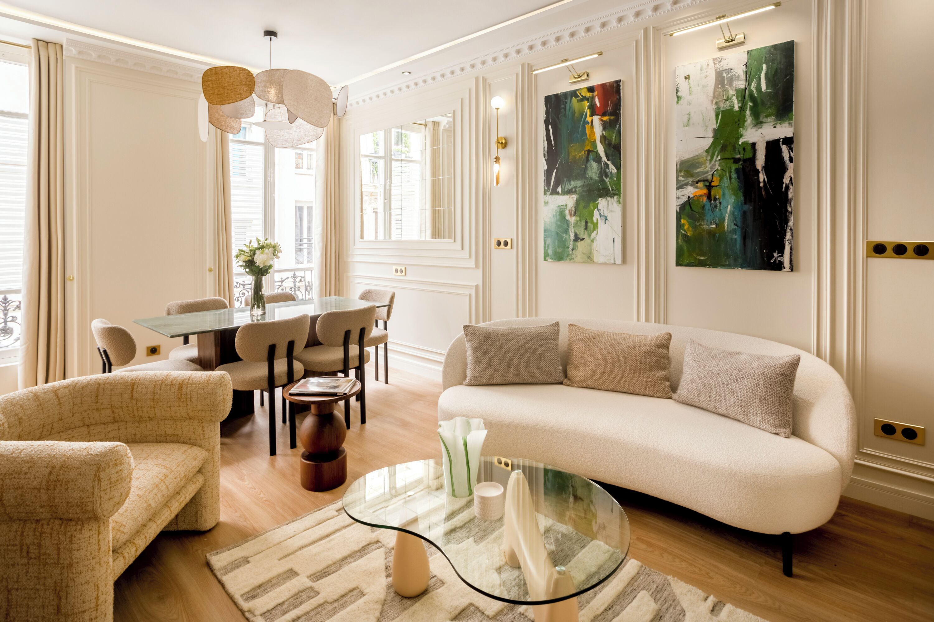 A modern living room with a sofa, chairs, a glass coffee table, and a dining area with a table and chairs.