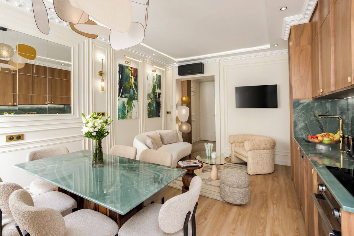Un espace repas moderne avec une table en verre, des chaises rembourrées et un vase de fleurs.