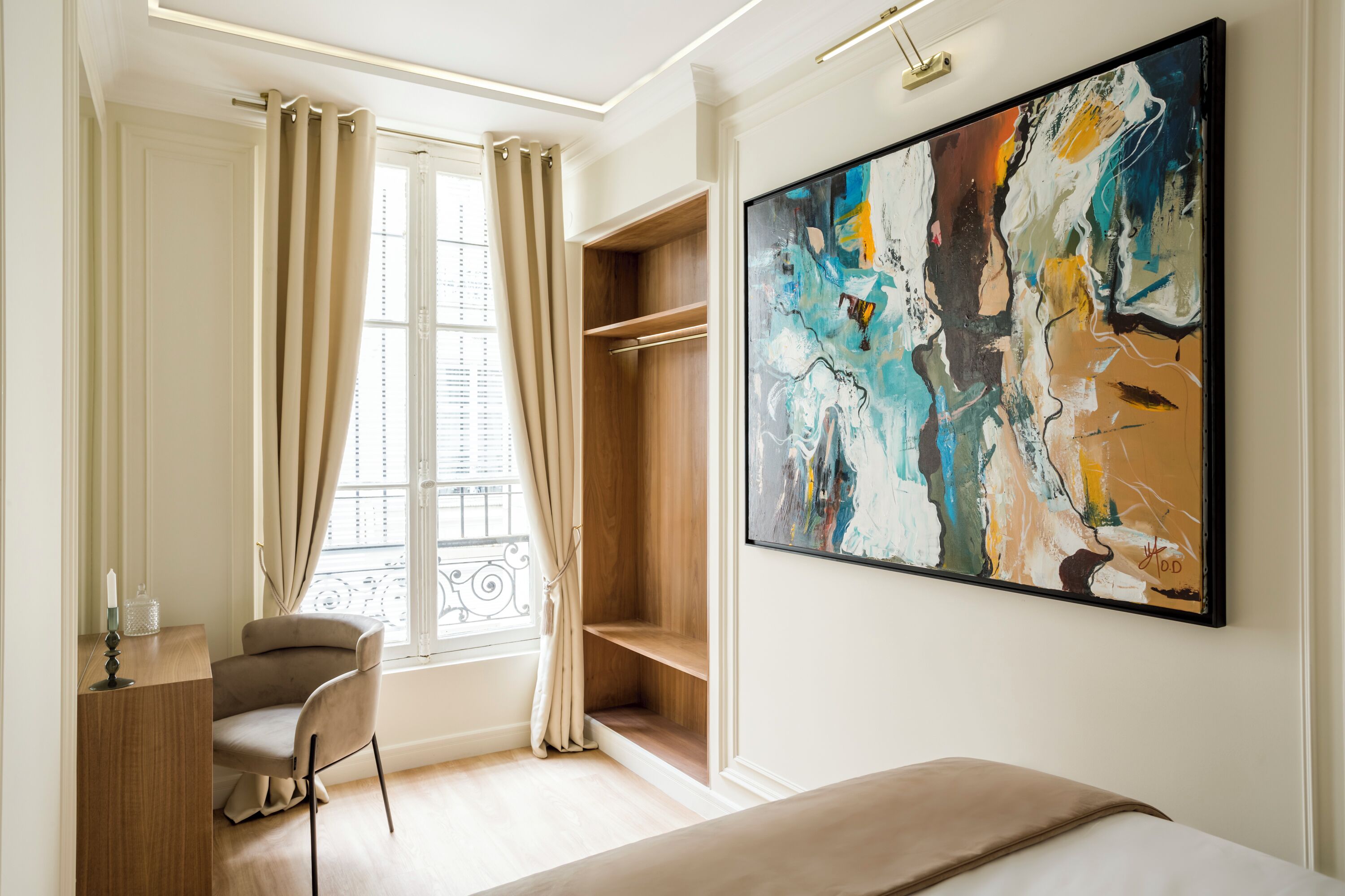 A modern bedroom with a bed, a desk, a chair, a large abstract painting, and a window with curtains.