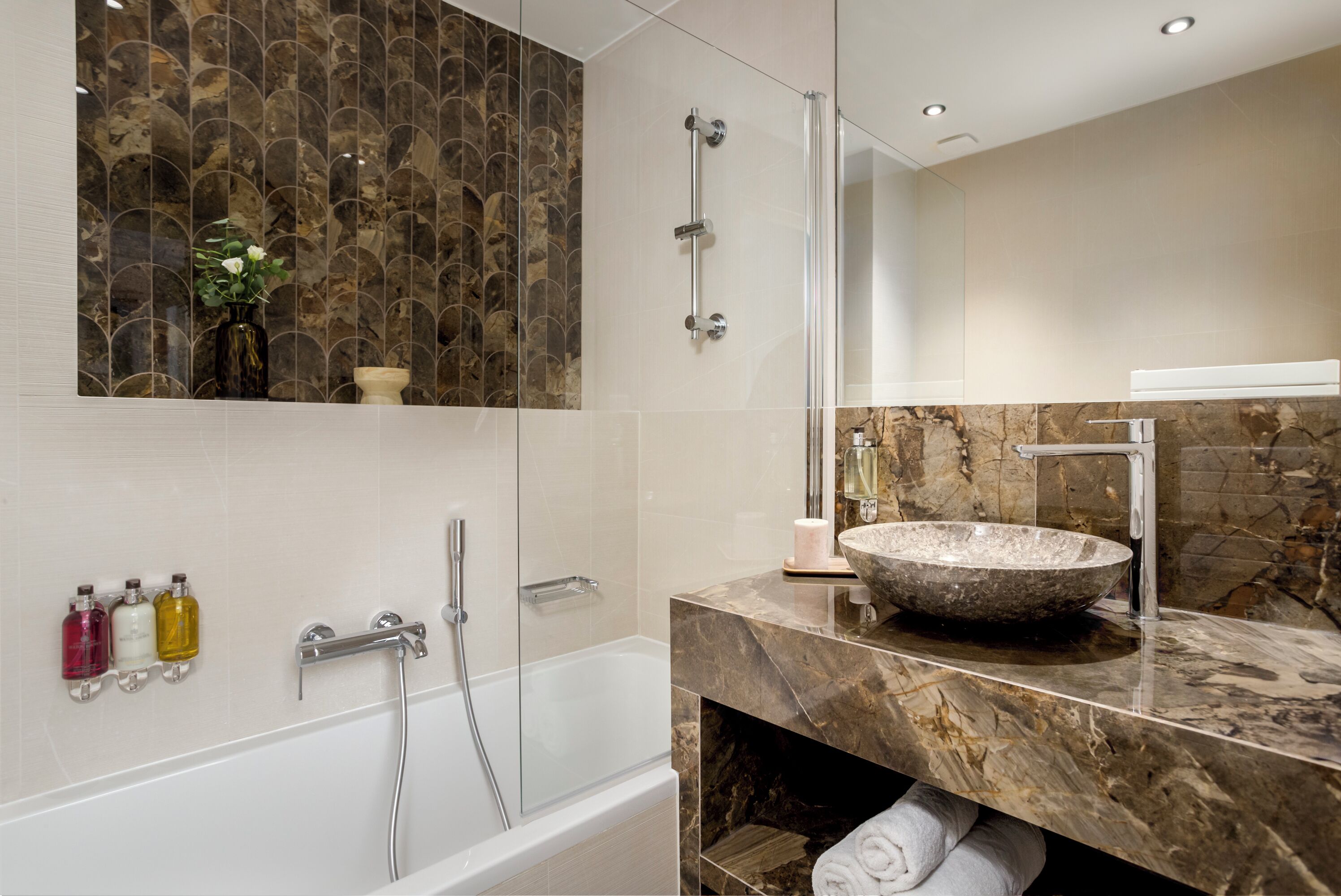 A modern bathroom with a glass-enclosed shower, a marble vanity, and a large vessel sink.