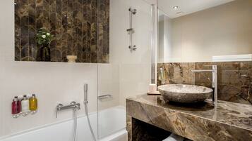 A modern bathroom with a glass-enclosed shower, a marble vanity, and a large vessel sink.