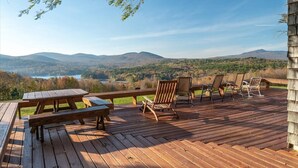 A wooden deck with picnic tables and chairs overlooking a mountainous landscape.