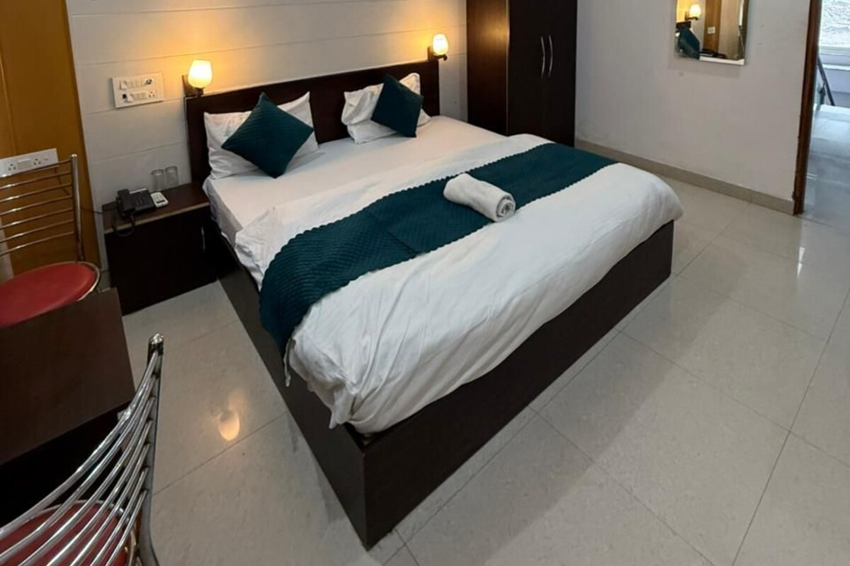 A hotel room with a bed, nightstands, a wardrobe, and a mirror.