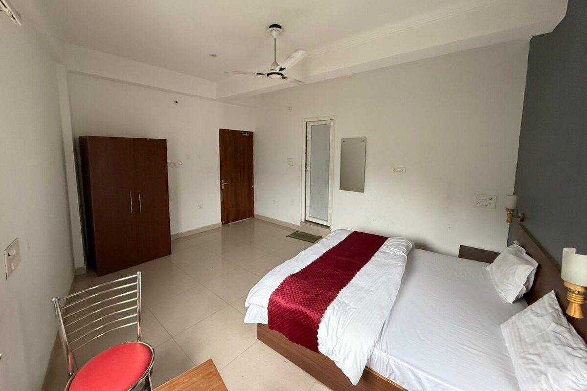 A hotel room with a bed, a chair, a wardrobe, and a door.
