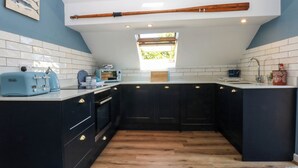 A modern kitchen with dark cabinets, a wooden countertop, and a skylight. - Borth Arian Boat House (Holyhead)
