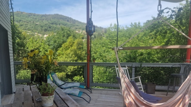 A wooden deck with a hammock, a table with a potted plant, and a chair. - ATYPICAL ARCHITECT-DESIGNED HOUSE (Vence)