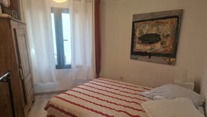 A bedroom with a bed, a painting on the wall, and a window with curtains. - ATYPICAL ARCHITECT-DESIGNED HOUSE (Vence)