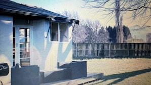 A house with a porch, a garage, and a fenced yard. - Green Keepers Bach (Methven)