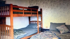 A bunk bed with a lower bunk and a sofa bed with cushions. - Green Keepers Bach (Methven)