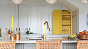 A kitchen with a central island, white cabinets, a yellow cabinet, and a copper pot. - The Lodge @Sunnybank House - unique country lodge overlooking Clifden Town (Clifden)