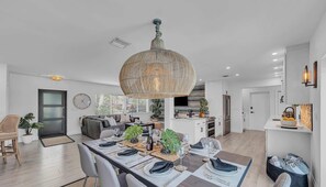 Une cuisine moderne avec des meubles blancs, un grand ßlot central et un coin repas aménagé pour accueillir six personnes.