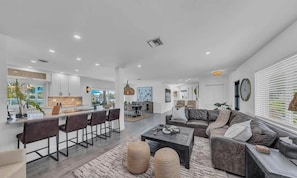 Uma sala de estar moderna com sofá, mesa de centro e banquetas.