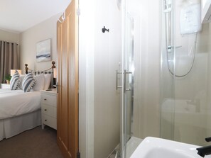 Una habitación de hotel con cama, mesita de noche, lámpara y un cuadro en la pared.