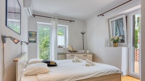 A bedroom with a bed, bedside table, lamp, and a window with curtains. - Captain's House - Sv. Jakov /w Terrace (Mali Losinj)