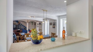 A kitchen with a fruit bowl, wine glasses, and a dining area with chairs and a table. - Captain's House - Sv. Jakov /w Terrace (Mali Losinj)