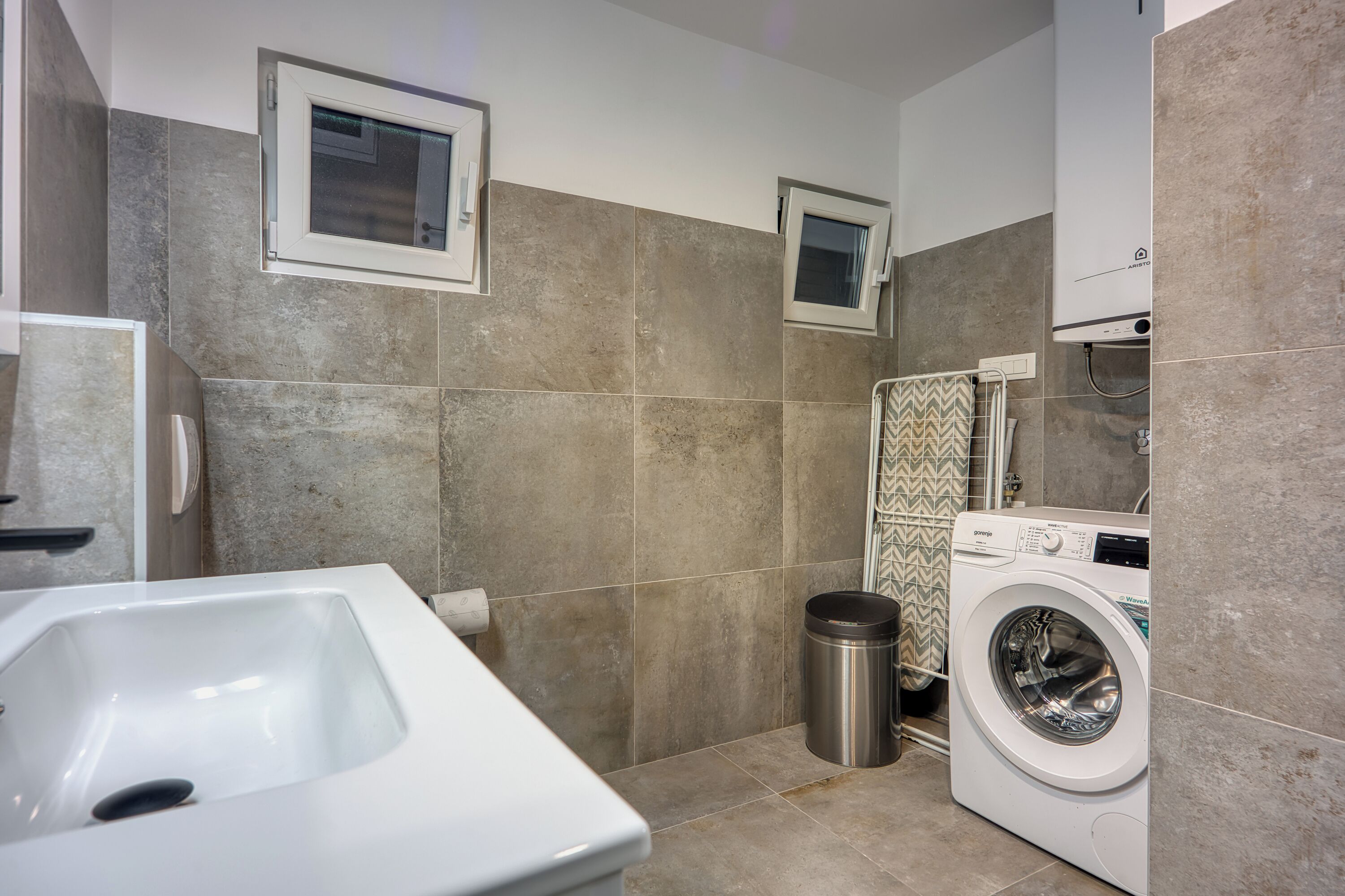 Une salle de bain avec une baignoire, un lave-linge et une petite fenêtre.