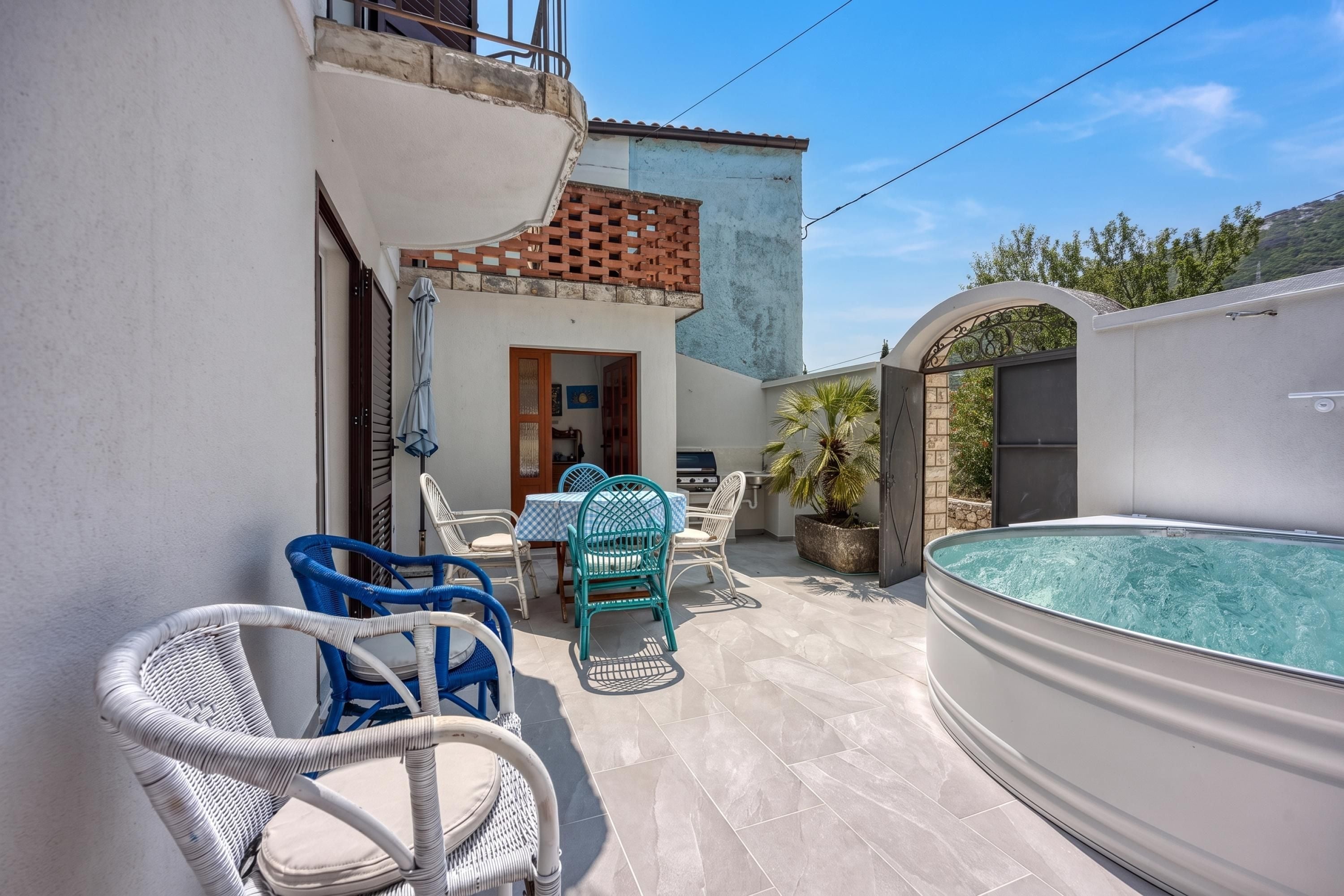 A patio area with outdoor seating, a swimming pool, and a building with a tiled roof.