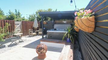 An outdoor patio area with a hot tub, seating, and a decorative plant.