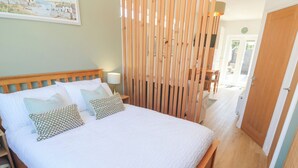 A neatly made bed with white bedding and patterned pillows, a wooden headboard, and a wooden floor. - Carn Brea (Redruth)