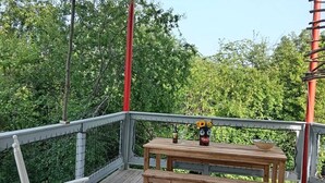 Puinen terassi, jossa on pöytä ja tuoleja, ja jonka ympärillä on metallinen kaide sekä katos.