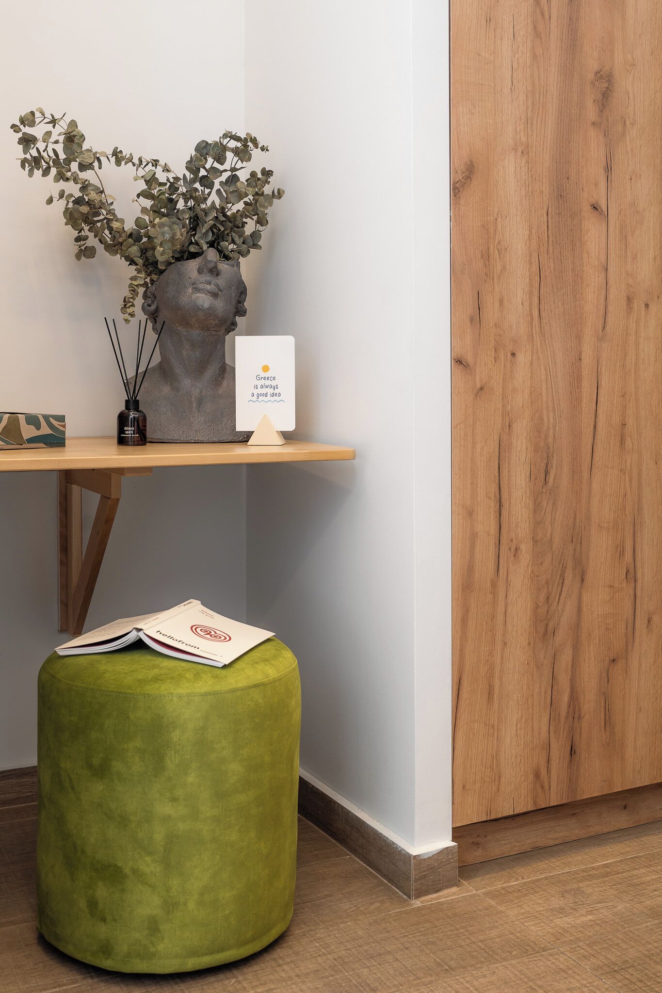 A wooden desk with a vase of green foliage, a small sign, and a book.