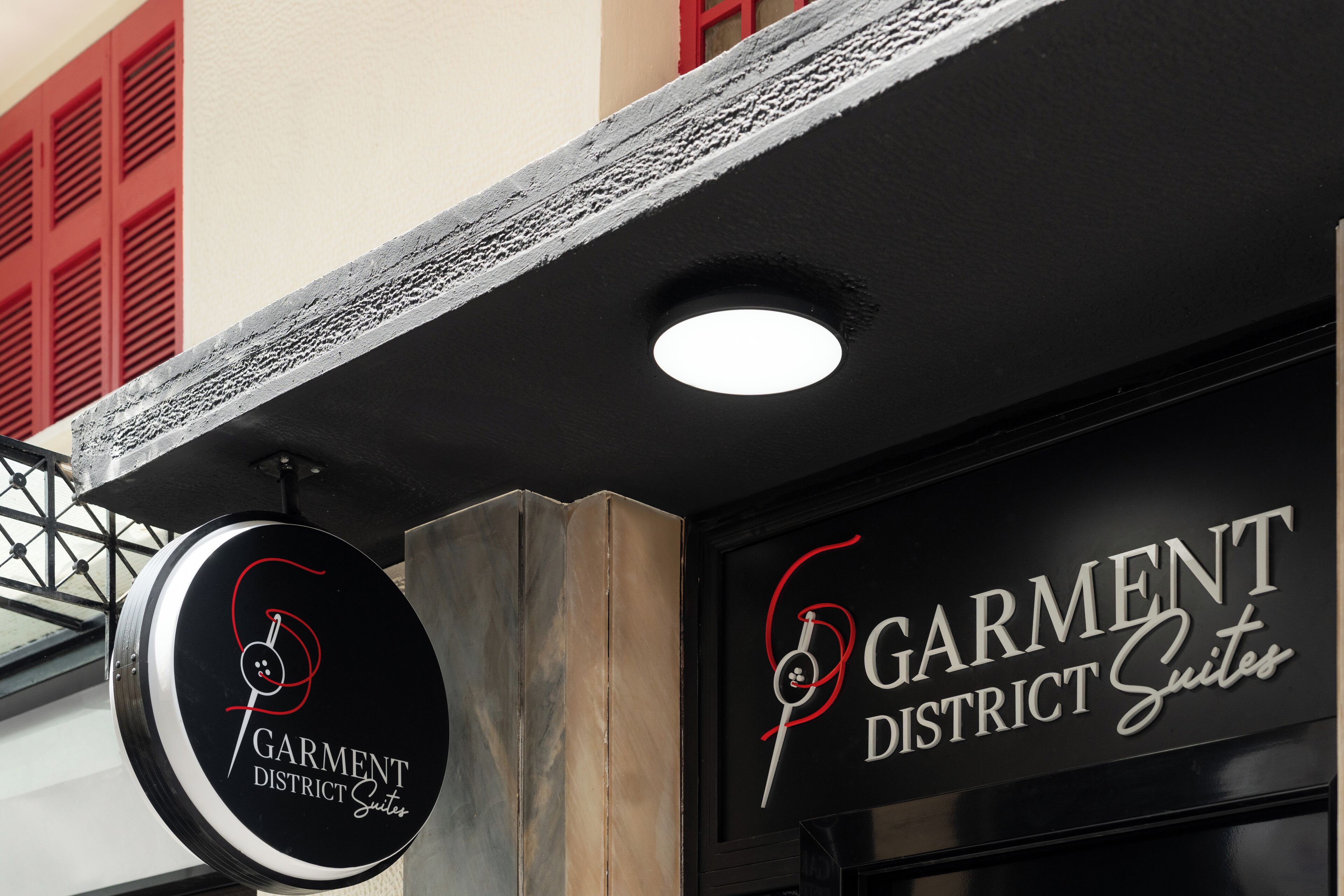 Un letrero de 'Garment District Suites' con un logo circular y un diseño estilizado.