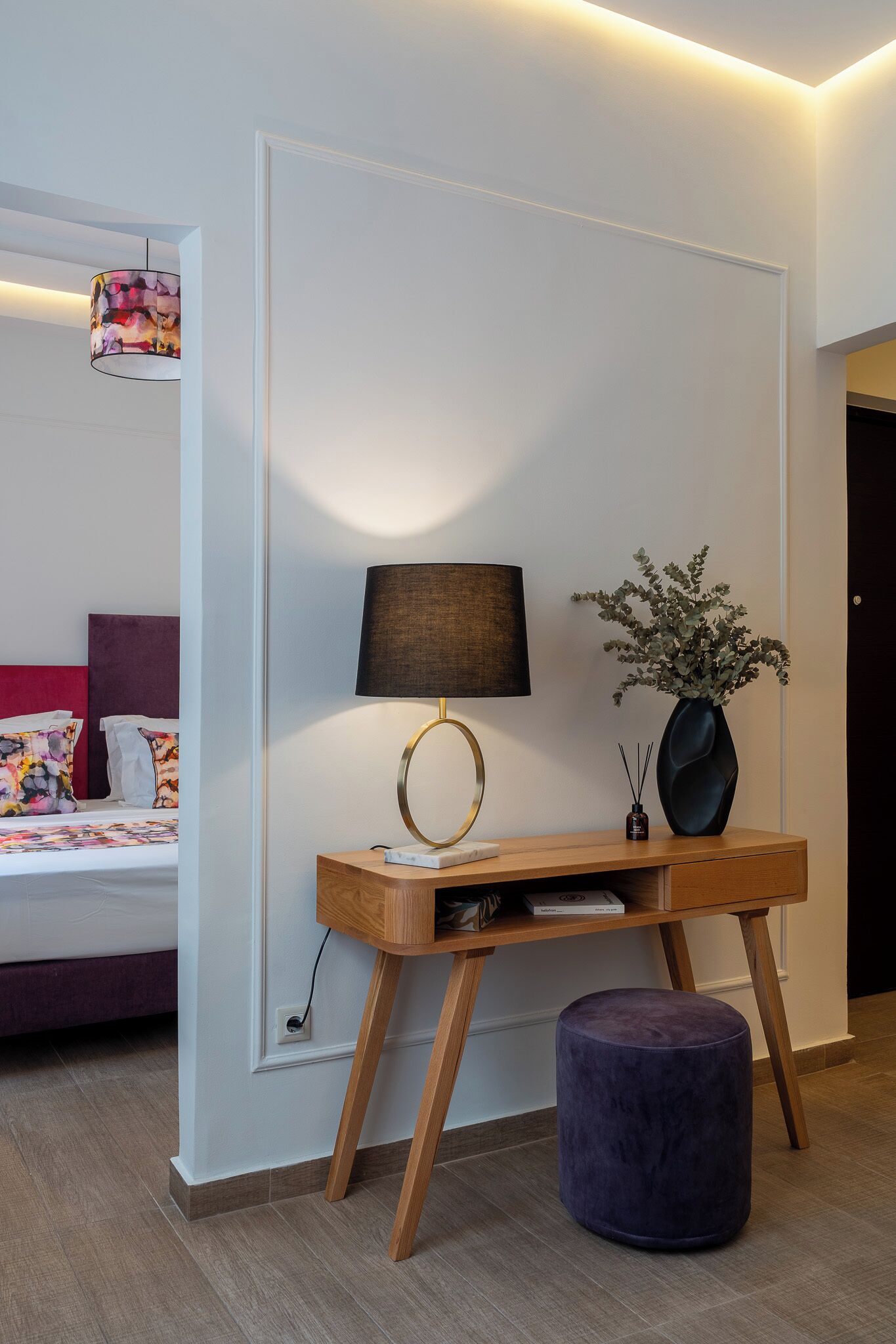 Un dormitorio con cama, mesita de noche, lámpara y un florero con plantas.
