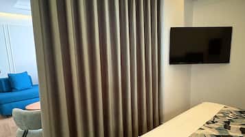 Un dormitorio con una cama, un televisor montado en la pared y una cortina.