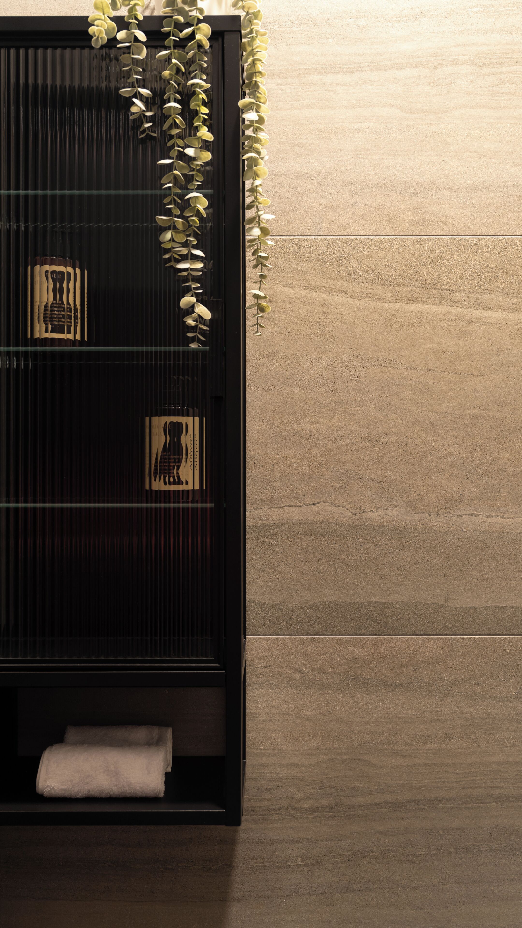A bathroom with a black vanity, a towel rack, and a decorative plant.