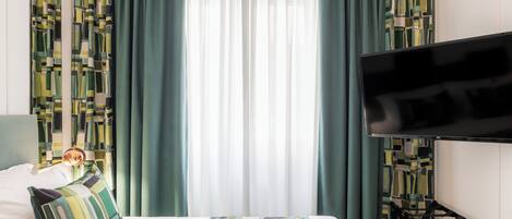Una habitación de hotel con una cama, un televisor y cortinas.