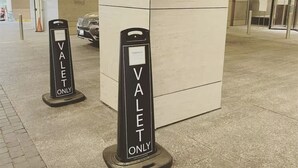 Zwei schwarze Poller mit der Beschriftung 'VALET ONLY' vor einem Gebäudeeingang.