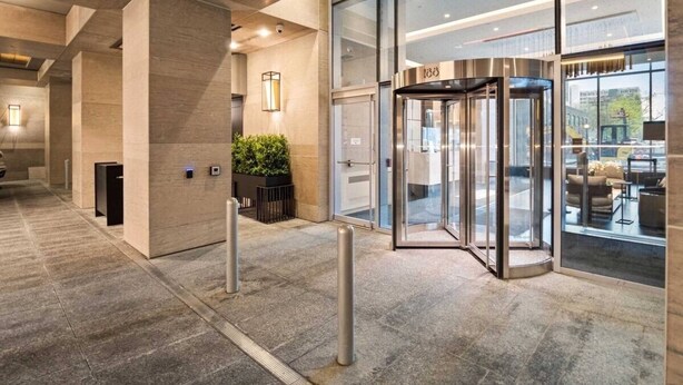 Eine moderne Hotelhalle mit einer Doppeltür, einem Empfangsbereich und einem Glastür zum Innenbereich.