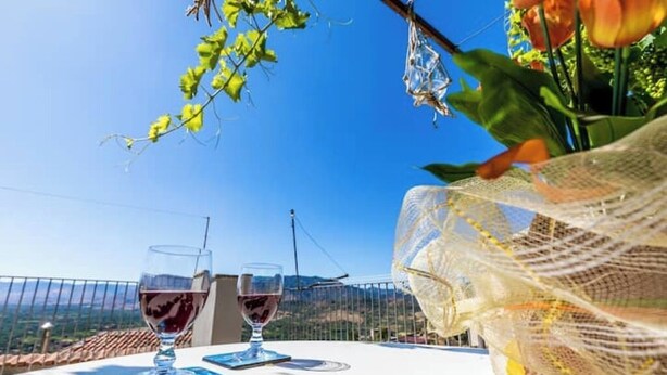 A table with two glasses of red wine, a smartphone, and a decorative item. - Maria Catena House (Castiglione di Sicilia)