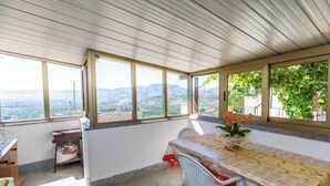 A room with a table and chairs, large windows with a view of mountains, and a ceiling with a ribbed design. - Maria Catena House (Castiglione di Sicilia)