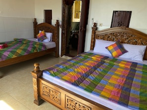 Dos camas de madera con colchas y almohadas de colores, un cabecero de madera y un piso de baldosas.