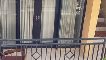 A balcony with a metal railing, a wooden chair, and a potted plant.