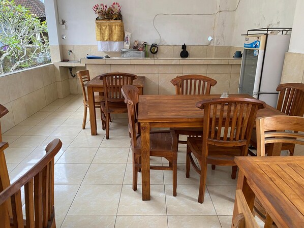 A wooden dining area with a tiled floor and a kitchen counter with various items. - Kabera Bungalow Ubud (Ubud)