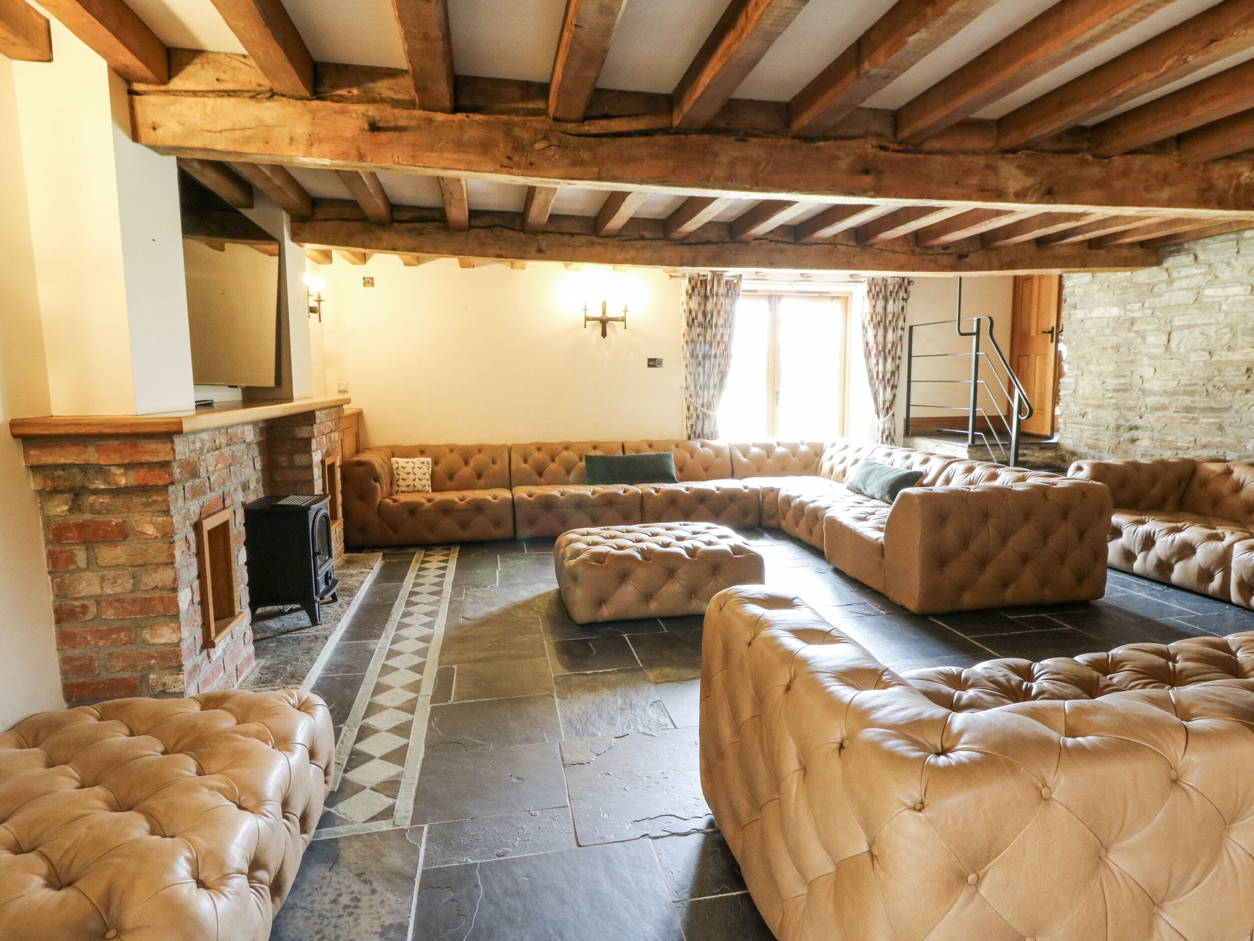 Una sala de estar acogedora con chimenea, un sofá modular y piso de baldosas de piedra.