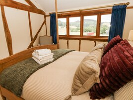 Un dormitorio con cama, una silla y ventana con vista al campo.