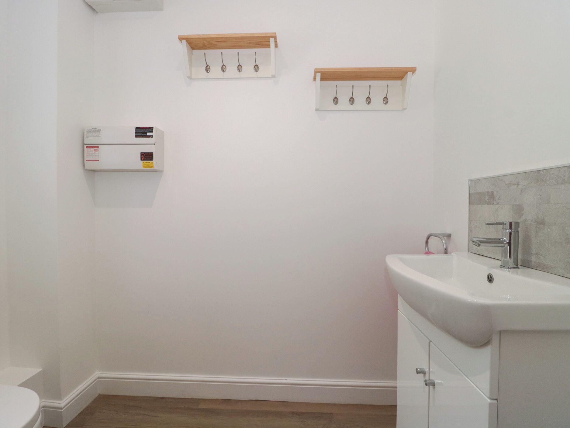 A bathroom with a toilet, a sink with a mirror, and two towel racks on the wall.
