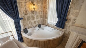 Un baño con bañera de madera, paredes de piedra y chimenea.