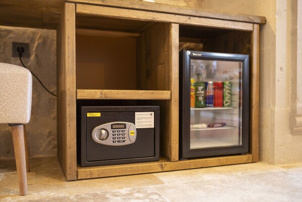 Un módulo de almacenamiento compacto con una caja fuerte Yale y un mini refrigerador que contiene bebidas.