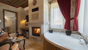 Una sala de estar con chimenea, una bañera grande y un comedor con una mesa dispuesta para dos.