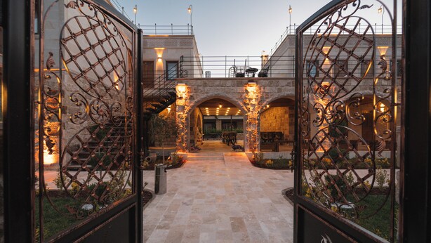 Un patio con un camino de piedra, estructuras en arco y portones de metal.