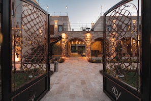 Un patio con un camino de piedra, estructuras en arco y portones de metal.